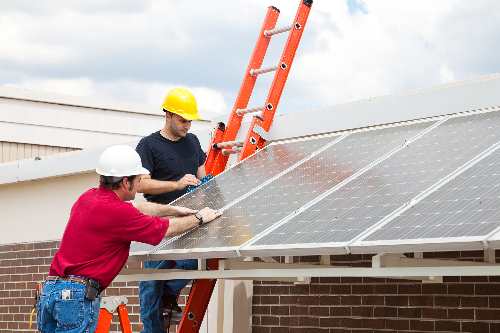 Workers Install Energy Efficient Solar Panels on the Roof of a Building.