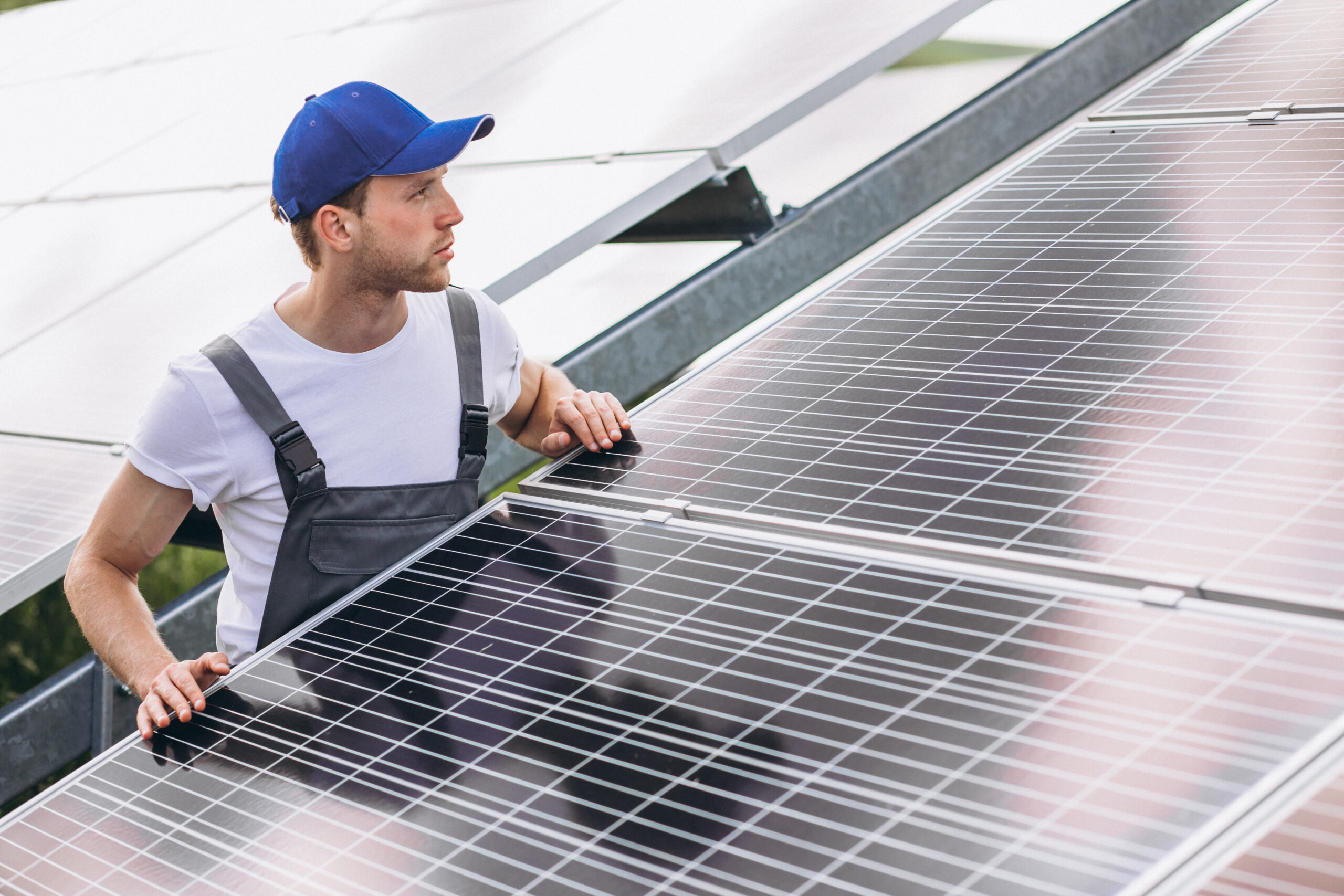 Man Worker in the Field by the Solar Panels.