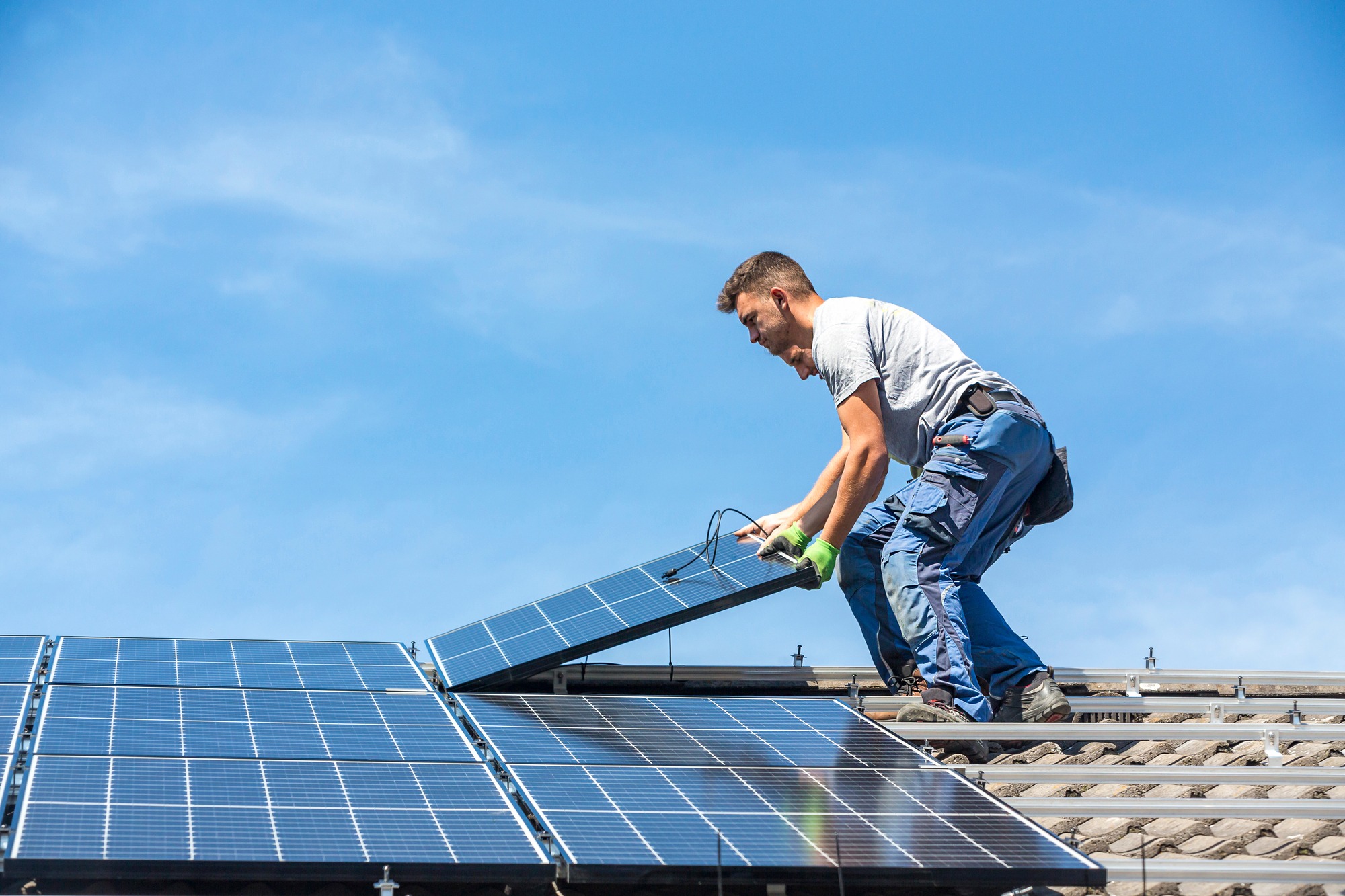 Installing Solar Photovoltaic Panel System. Solar Panel Technician Installing Solar Panels on Roof. Alternative Energy Ecological Concept.