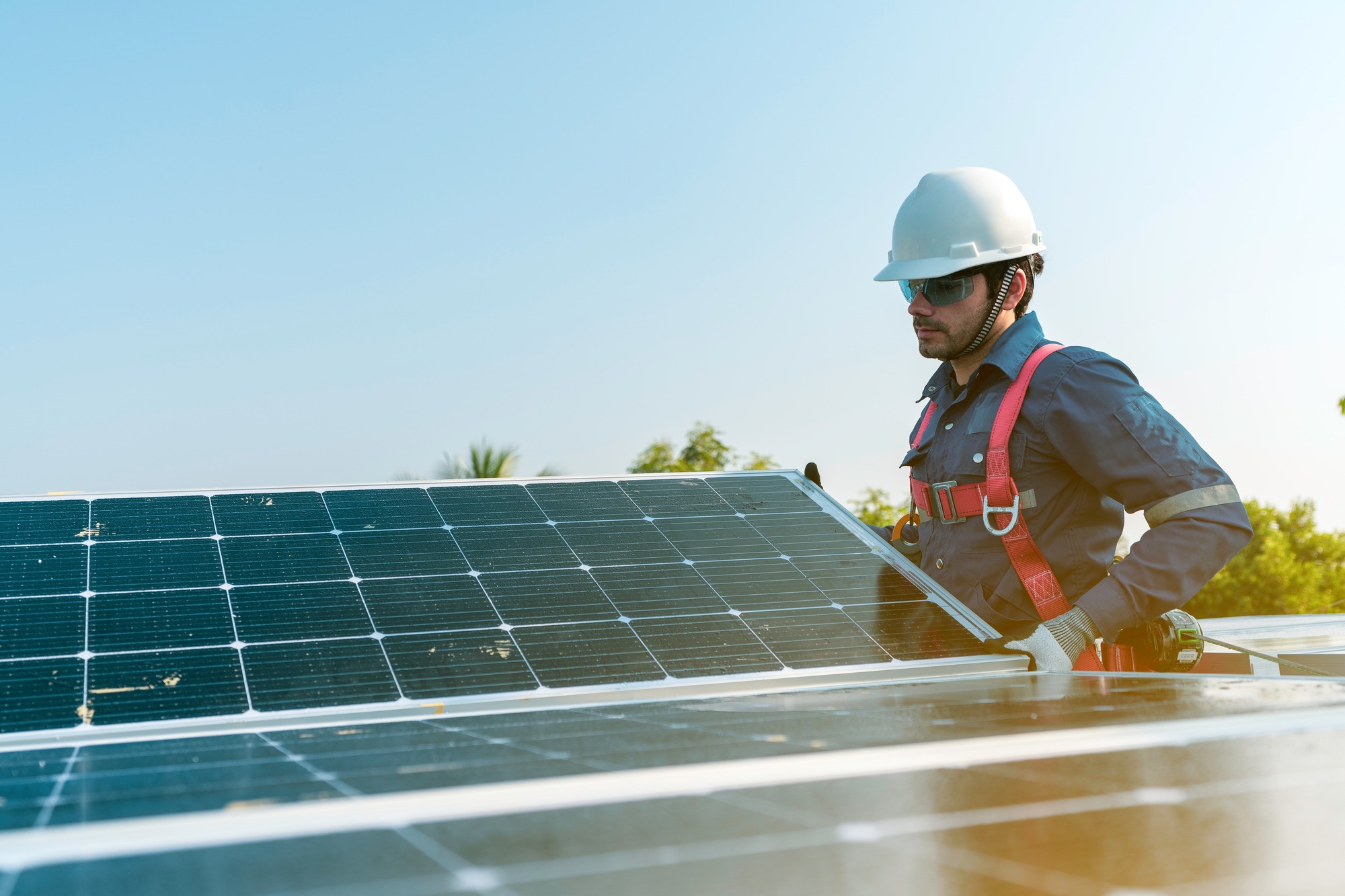 A Technician Installing the Solar Panels at Roof Top of Home and Home Office.